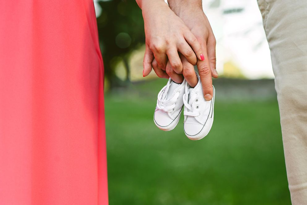 Nahaufnahme: Pärchen hält Kinderschuhe in der Hand