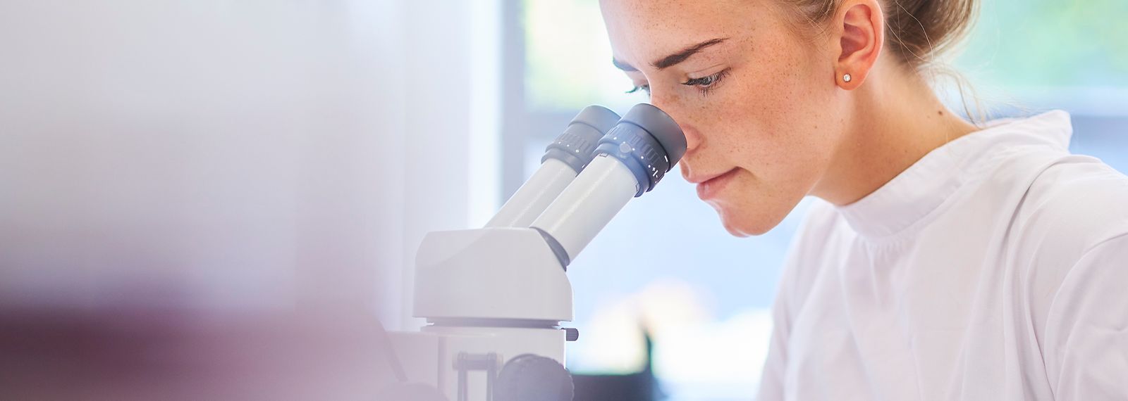 Eine Wissenschaftlerin blickt in ein Mikrokop