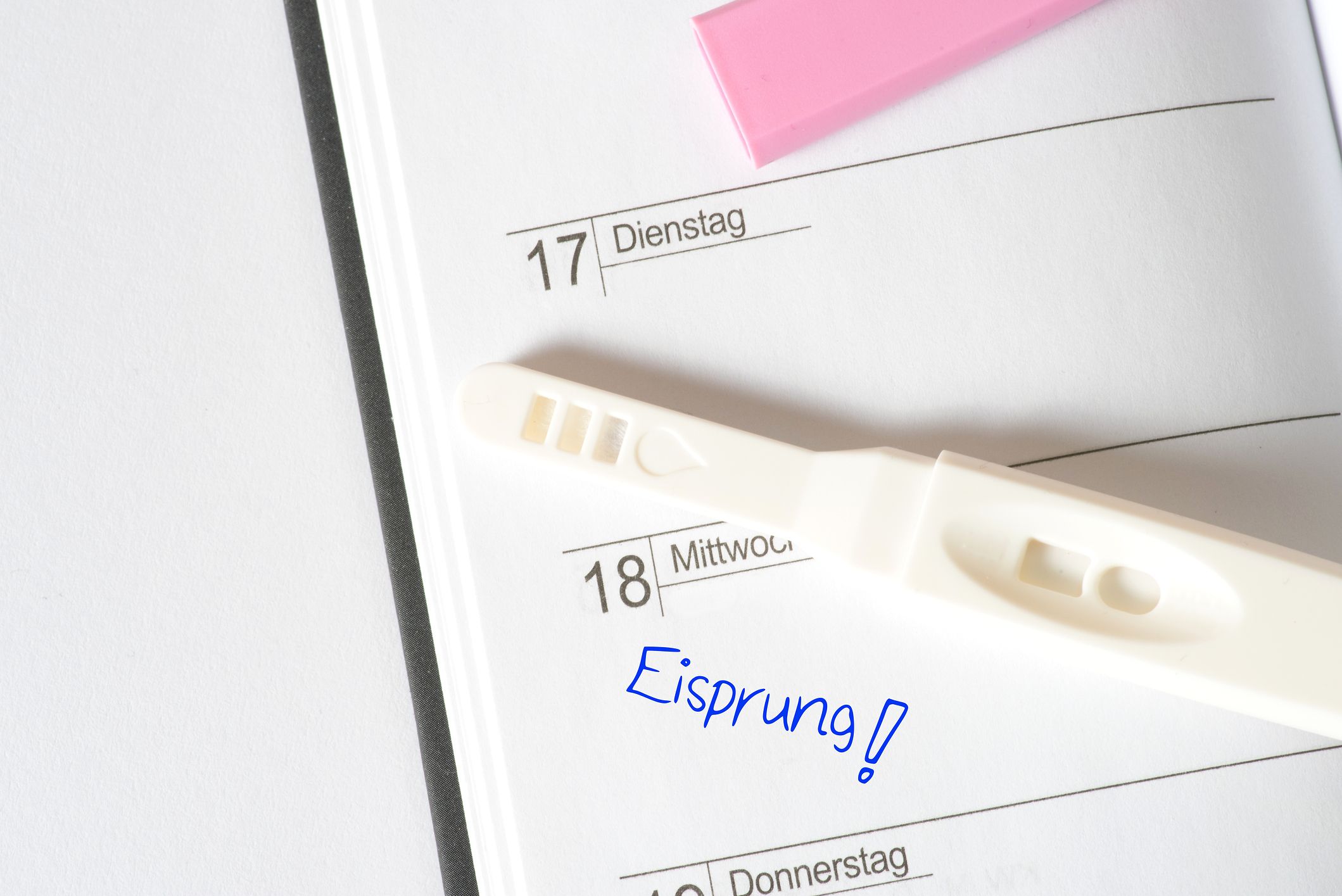 Schwangerschaftstest liegt auf Kalender in dem bei einem Tag steht: Eisprung