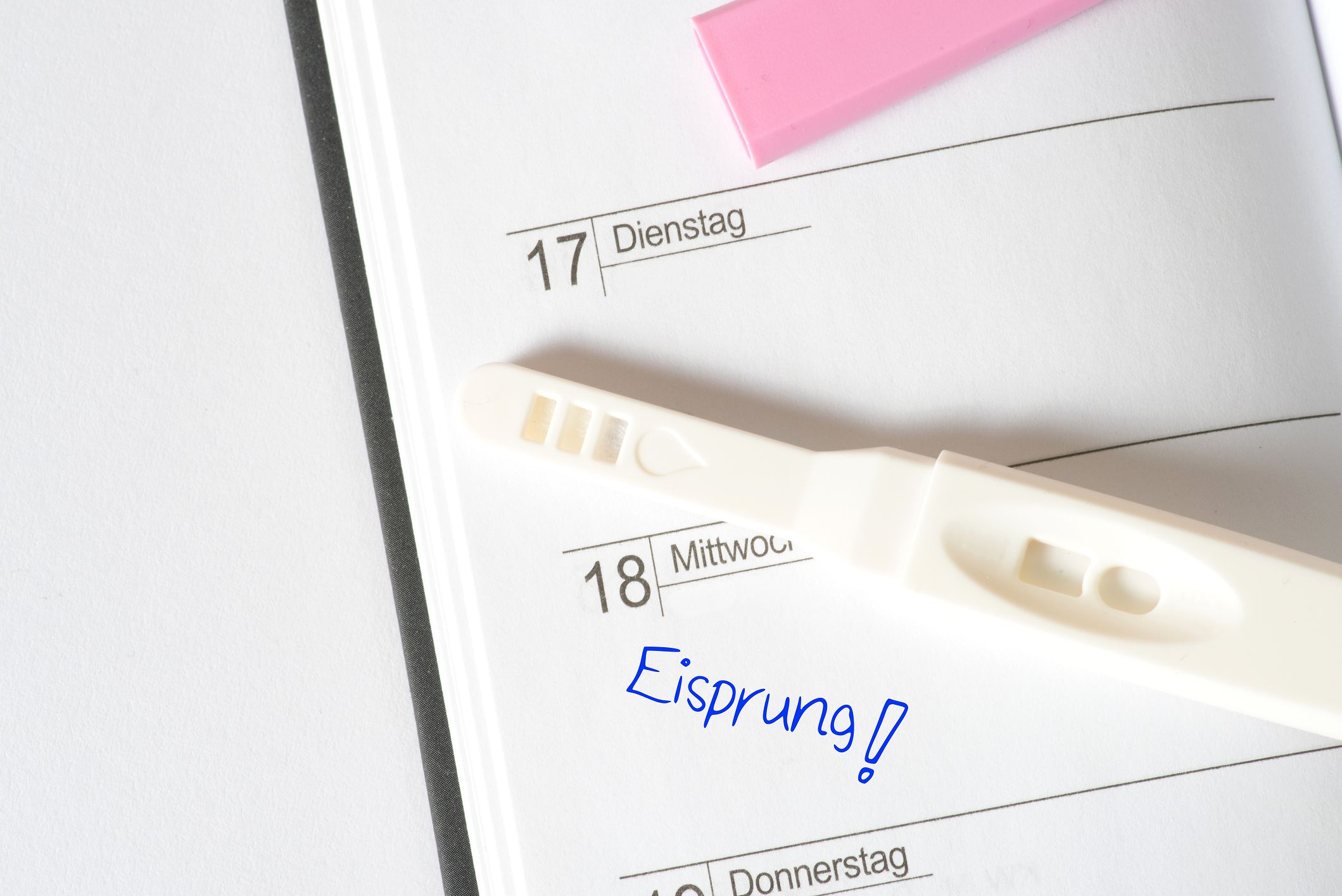 Schwangerschaftstest liegt auf Kalender in dem bei einem Tag steht: Eisprung