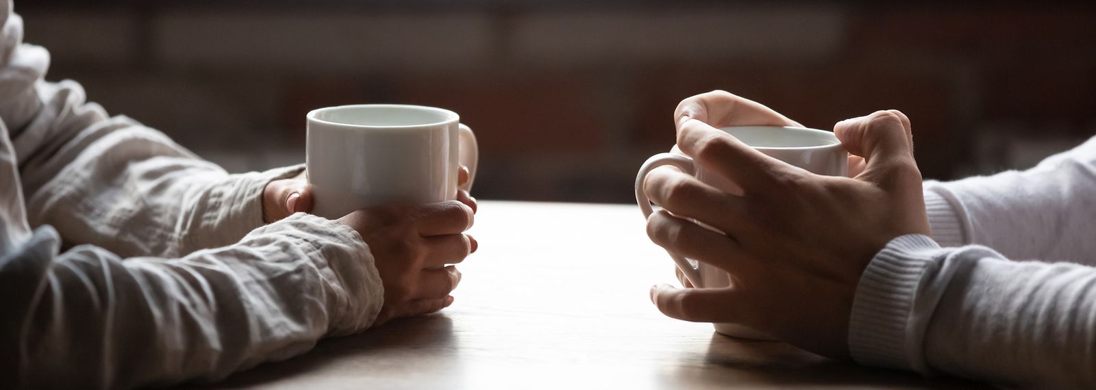 Zwei Personen halten Teetasse fest bei Beratung