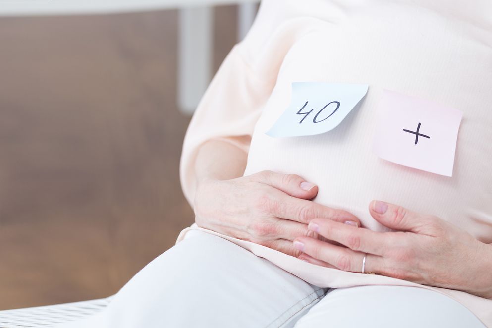 Post-Its kleben auf dem Bauch einer schwangeren Frau, darauf steht "40+"