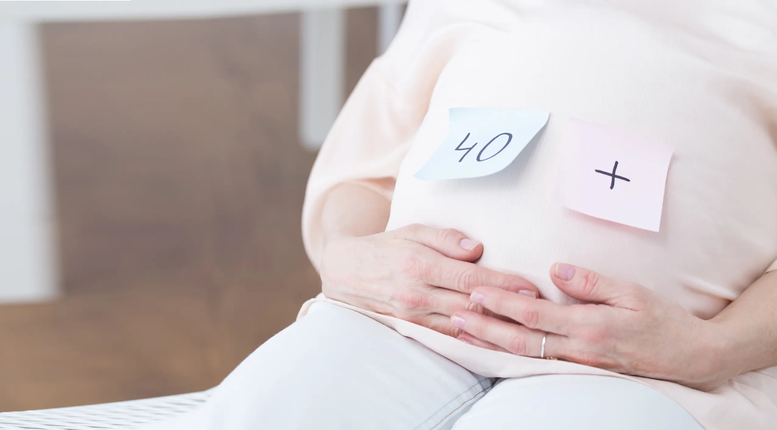 Post-Its kleben auf dem Bauch einer schwangeren Frau, darauf steht "40+"