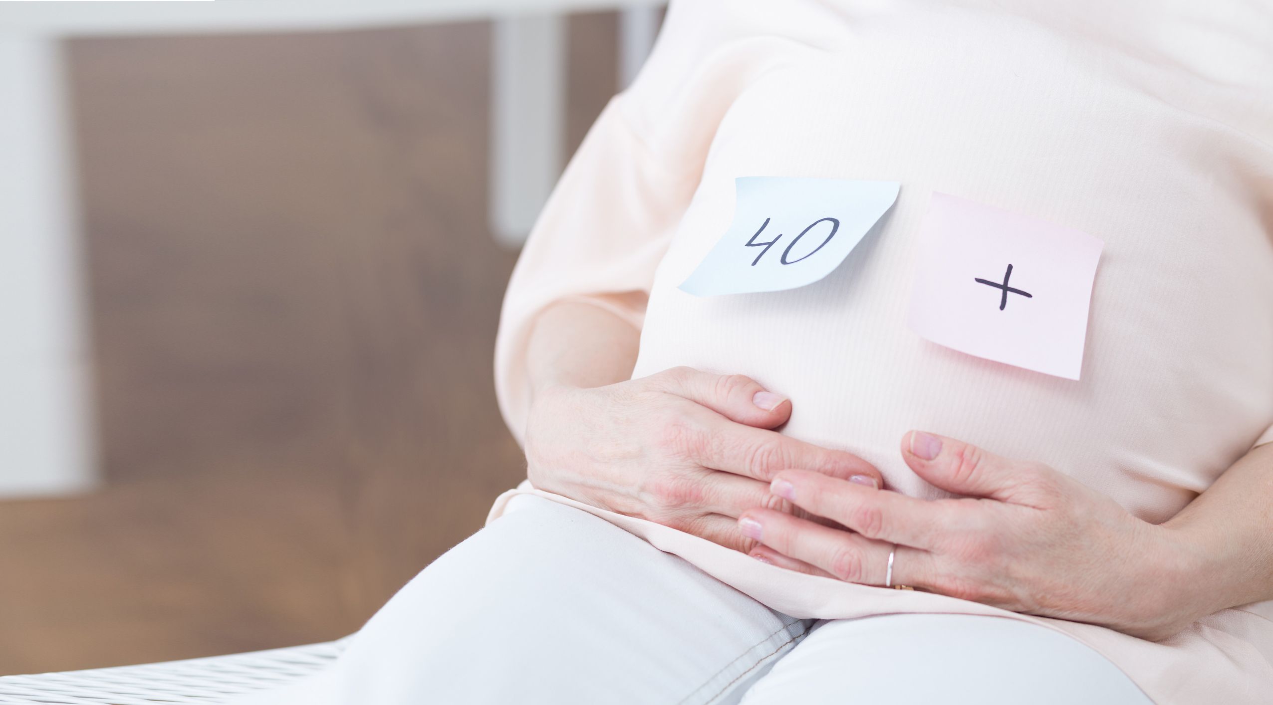 Post-Its kleben auf dem Bauch einer schwangeren Frau, darauf steht "40+"