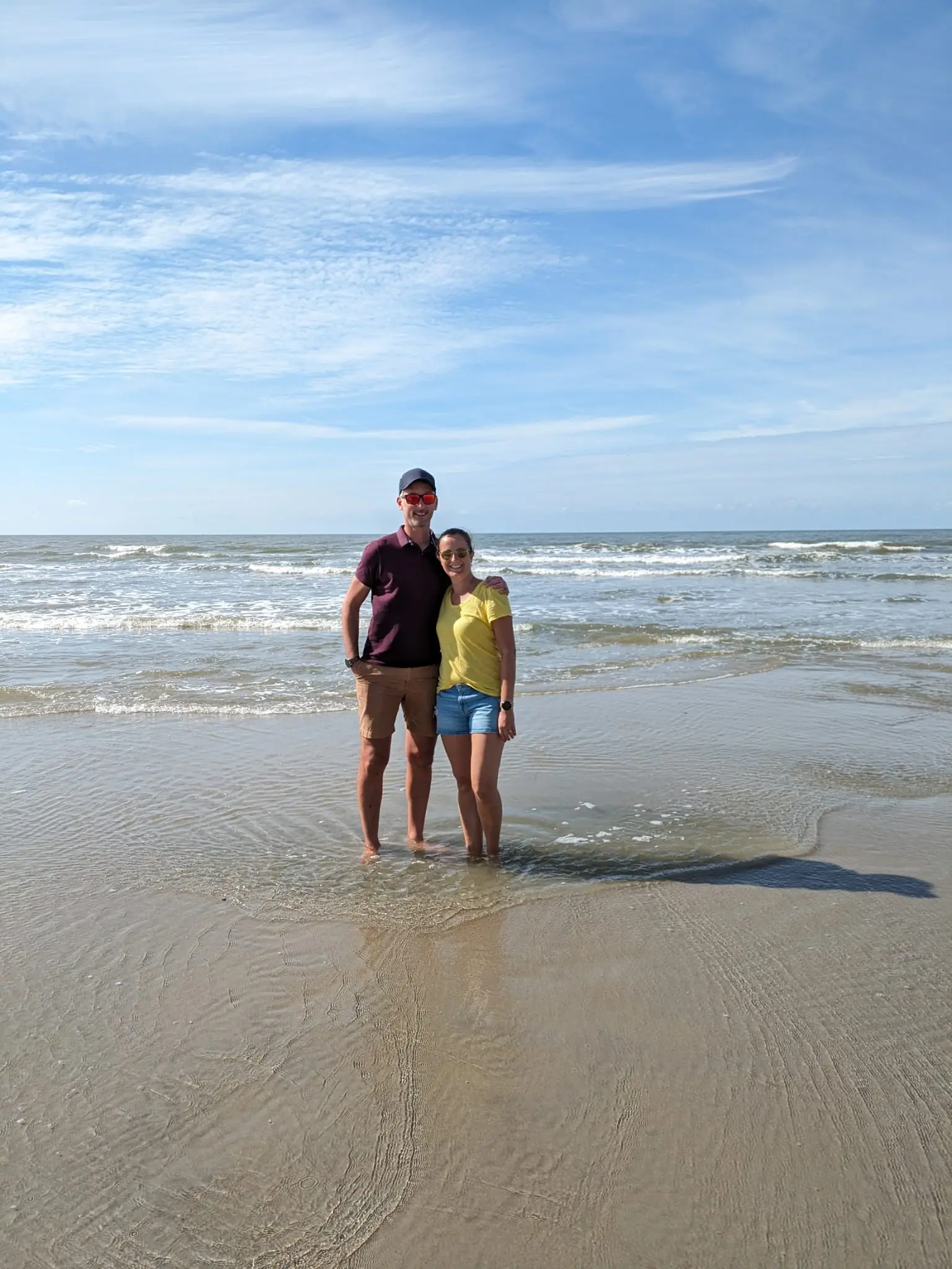 Ein junges Paar steht am Strand mit den Füßen im Wasser