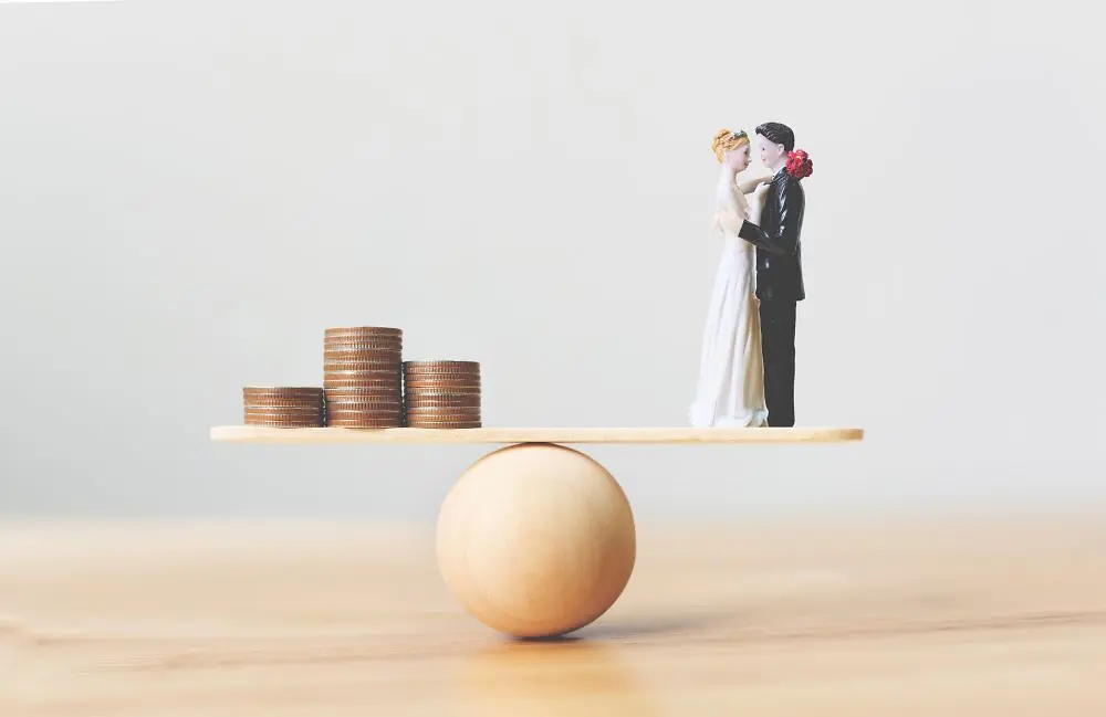 Ein Plastik-Hochzeitspaar und Münzen auf einer Waage