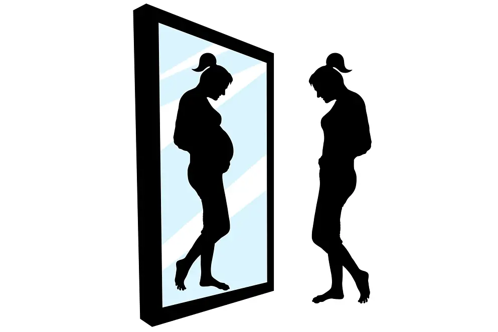 Frau vor einem großen Spiegel, sieht ein Spiegelbild einer schwangeren Frau