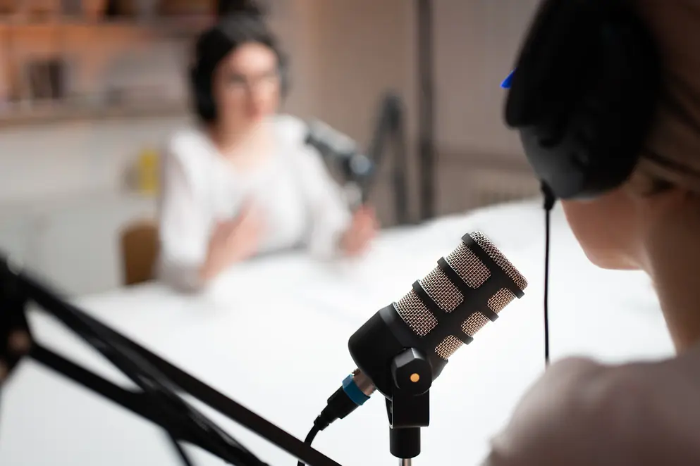 Nahaufnahme einer unkenntlichen Frau und eines Mikrofons in einem Podcast.