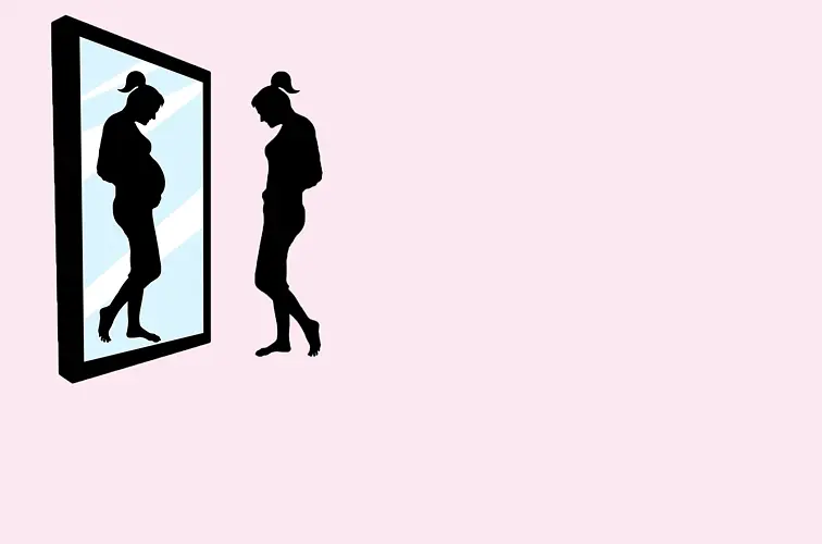 Schattenbild einer Frau, die sich in ihrem Spiegelbild mit einem schwangeren Bauch sieht